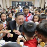 Beaming Kim Jong-un surrounded by flood-stricken North Korean children grasping for food