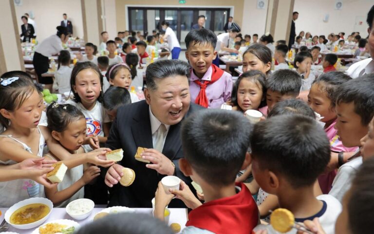 Beaming Kim Jong-un surrounded by flood-stricken North Korean children grasping for food